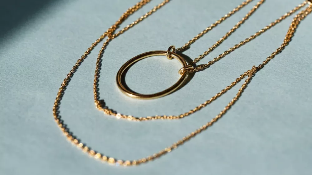 چندین زنجیر طلای مینیمال روی یک زمینه آبی رنگ