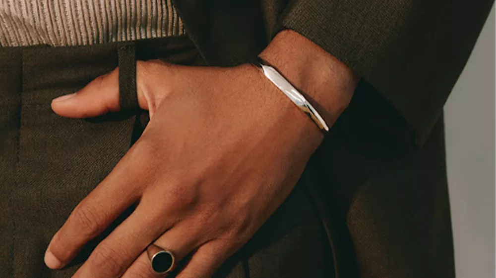 دستبند Gabriel Hexagon Diamond در دست مردی با کت و شلوار قهوهای تره