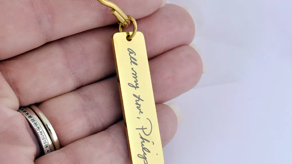 جاکلیدی طلایی مستطیلی حکاکی شده روی دست یک مرد