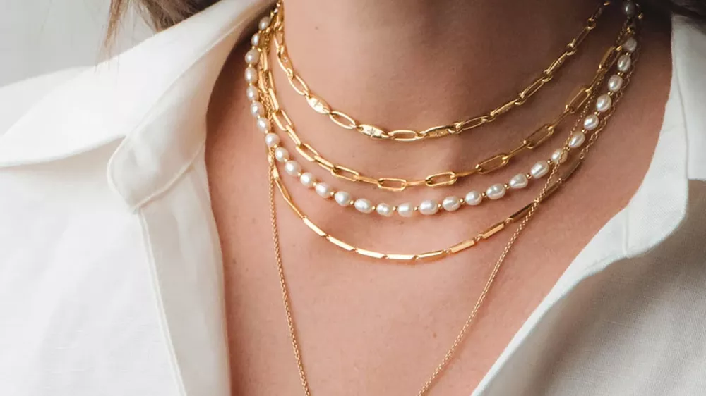 زنجیرهای چندلایه در گردن زنی با پیراهن سفید