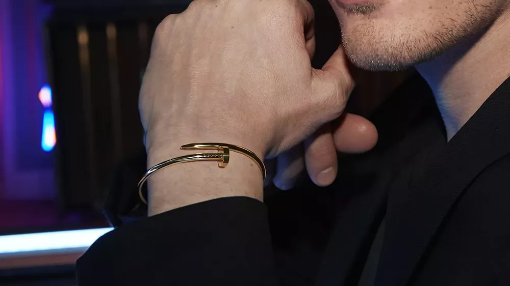 دستبند طلا مردانه کارتیه روی دستی که زیر چانه قرار گرفته