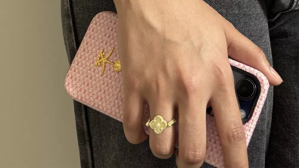 انگشتر طلا با طرح ونکلیف در دست یک زن با گوشی موبایل