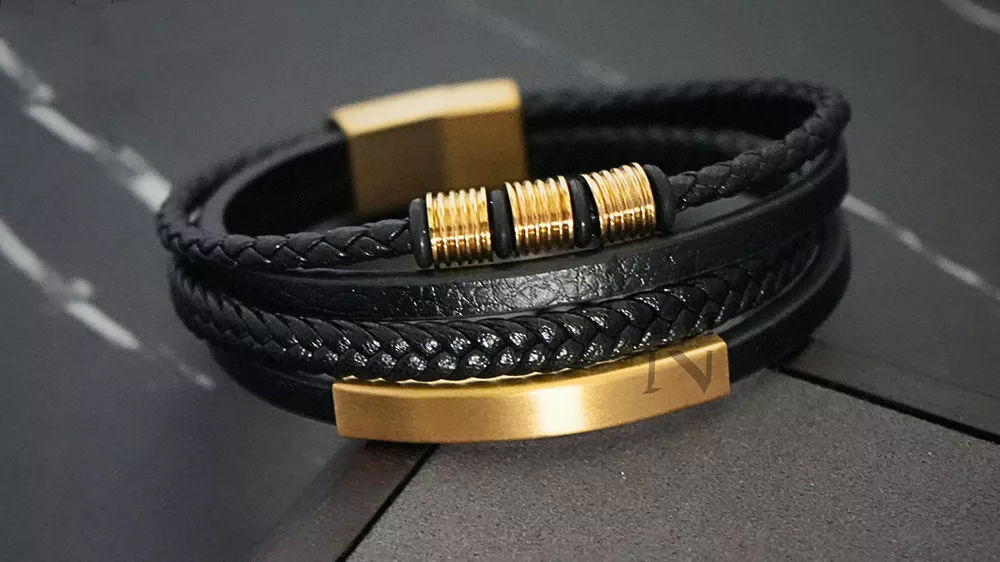 دستبند طلا مردانه بند چرمی مشکی با پسزمینه خاکستری