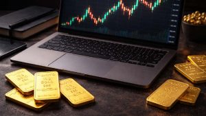 چندین شمش طلا در اطراف یک لبتاب که روی دسکتاپ آن نمودار قیمتی با کندل‌هاست