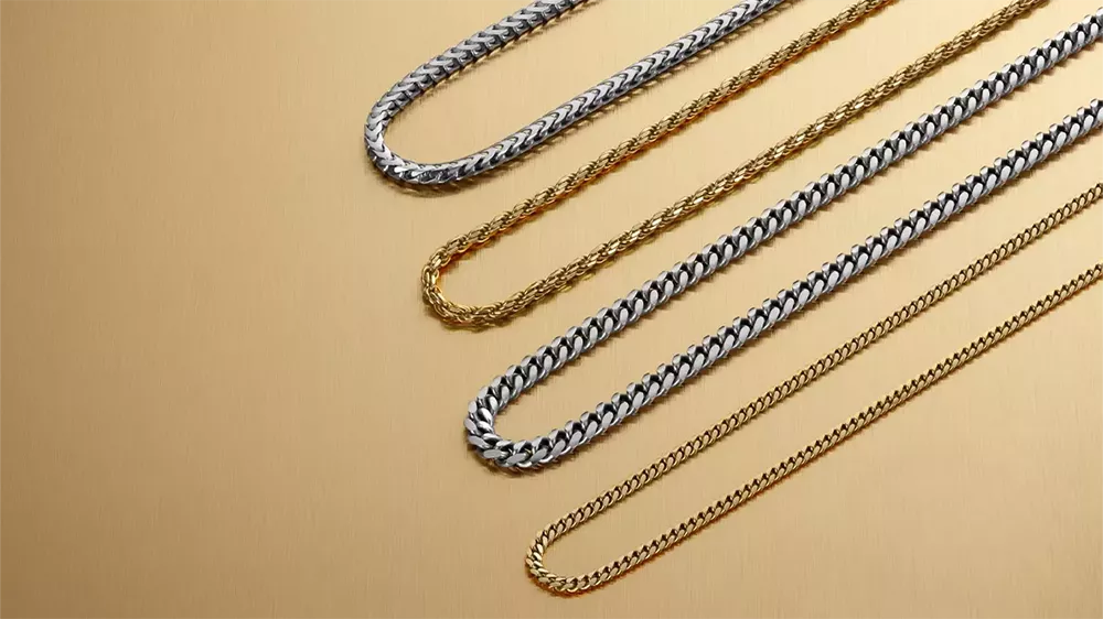 چندین زنجیر طلای سفید و طلای زرد در کنار هم با پسزمینه طلایی